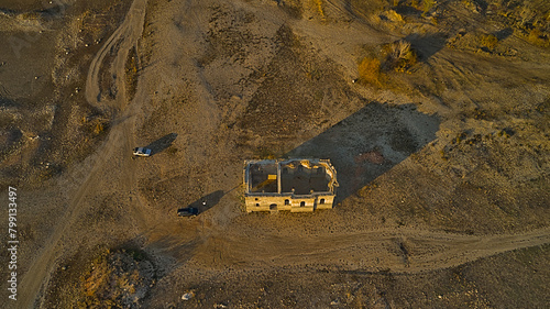 Traces of dirt roads and ruined houses mark the site of a former village, now submerged beneath the reservoir formed by a breached dam, with only the surviving church of St. Ivan Rilski, Bulgaria