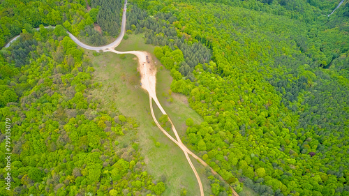 Dirt roads in the forests amidst the mountains seen from above. Aerial photo taken from a drone.