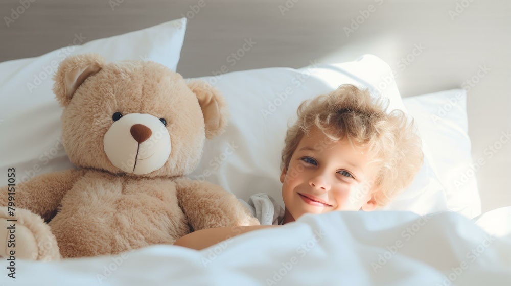 A young boy smiling while lying in bed with his teddy bear
