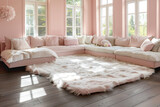 A spacious, pastel pink living room interior with large windows. A fluffy, white rug covers the dark, hardwood flooring, complementing the soft pink walls. A cream corner sofa,