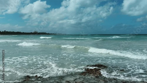 Rocky Cuban beach in Varadero, Cuba, on a cloudy day, when the sun breaks through the clouds, you can see the waves and ocean expanses. Turquoise waves. Stone slabs on the beach in the ocean. 4K	 photo