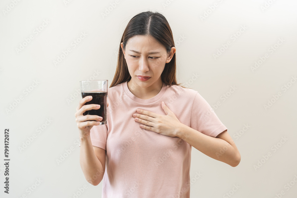 Acid reflux disease, suffer asian young woman, girl hand holding a glass of cola, have symptom gastroesophageal, heartburn pain on chest when drinking sparkling, soft water. Healthcare medical concept Acid reflux disease, suffer asian young woman, girl hand holding a glass of cola, have symptom gastroesophageal, heartburn pain on chest when drinking sparkling, soft water. Healthcare medical concept