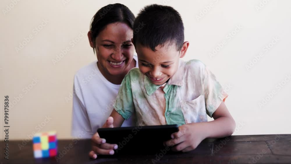 Latin mother and son having fun playing with tablet computer at home. Family relationship and technology concept Latin mother and son having fun playing with tablet computer at home. Family relationship and technology concept