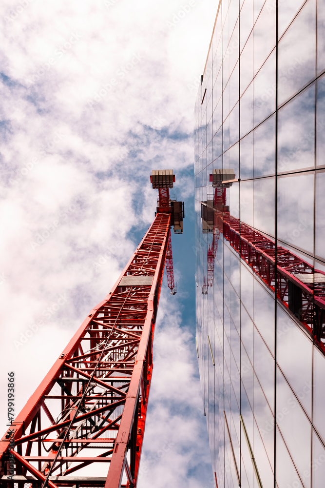 Obraz premium Red crane reflected on glass building 