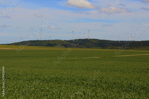 Image of wind generators against a background of green fields, green energy.