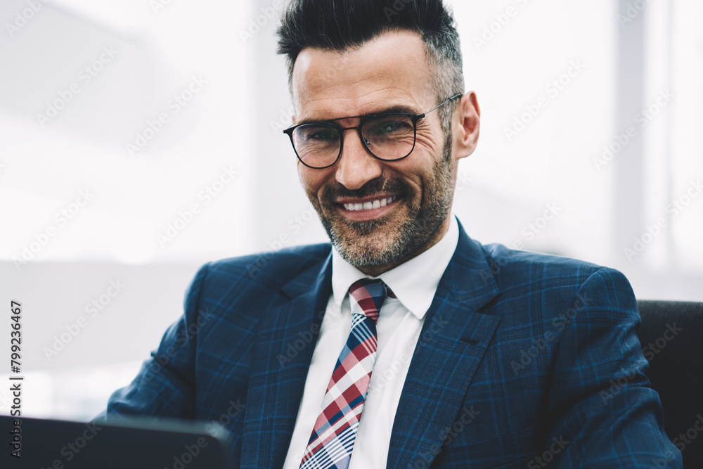 Half length portrait of successful businessman middle aged smiling at camera while working on accounting report at laptop computer connected to wireless 4g internet.Prosperous proud ceo checking mail Half length portrait of successful businessman middle aged smiling at camera while working on accounting report at laptop computer connected to wireless 4g internet.Prosperous proud ceo checking mail