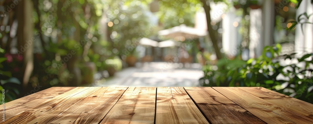 Empty wooden table top with blur background of green garden and coffee shop interior