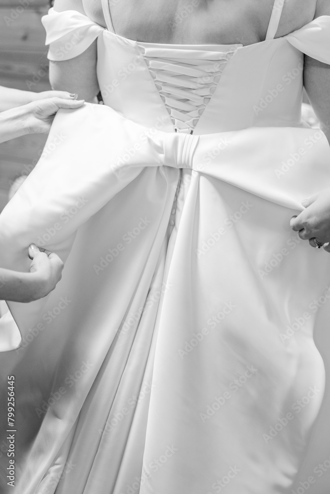 The black and white back of a plus sized bride's wedding dress that has a corset and bows