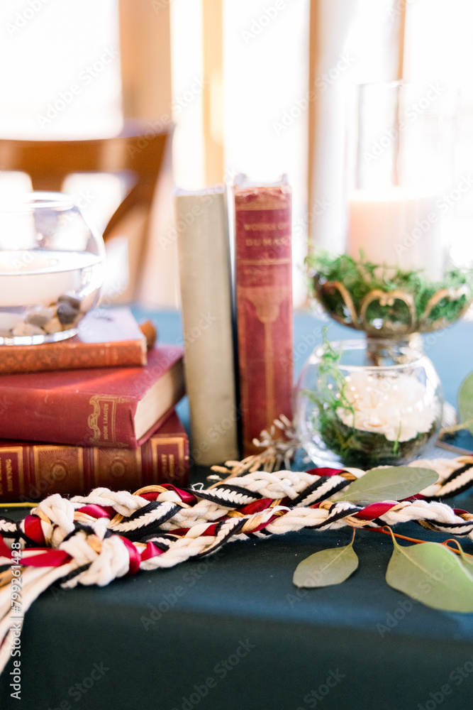 A unity rope is on a table with stacked old books in a romantic table setting at a book-themed wedding