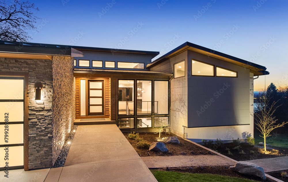 Beautiful modern style luxury home exterior at sunset with glowing interior lights.