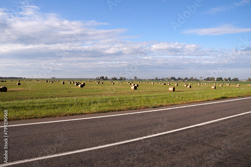 Rural landscape road near a field with hay rolls