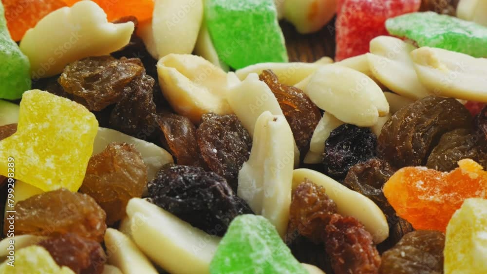 Mix of multi-colored dried fruits and nuts scattered on a wooden surface, rotating in a circle Mix of multi-colored dried fruits and nuts scattered on a wooden surface, rotating in a circle
