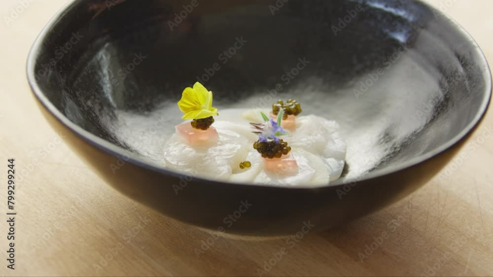 Person decorating scallops with flowers in bowl Person decorating scallops with flowers in bowl
