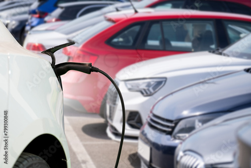 Close-up of a charging electric car on the background of parked cars