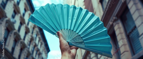 A hand holding a paper fan, summer in the city photo