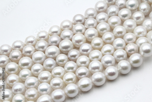 Chinese round freshwater white pearls on strands ready to become a necklace, some of the favorite materials for jewelry on white background. An organic gem that brides love for weddings.