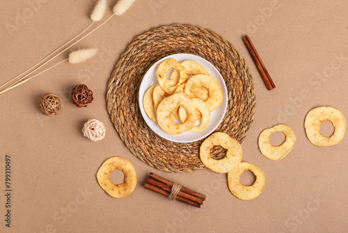 Sweet tasty apple chips in a white ceramic plate from above on a light beige background in rustic style. Healthy snack, top view.