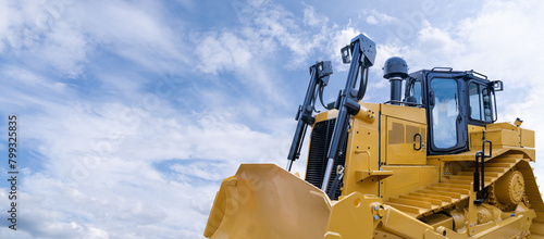 Heavy yellow bulldozer on a background of blue sky. photo