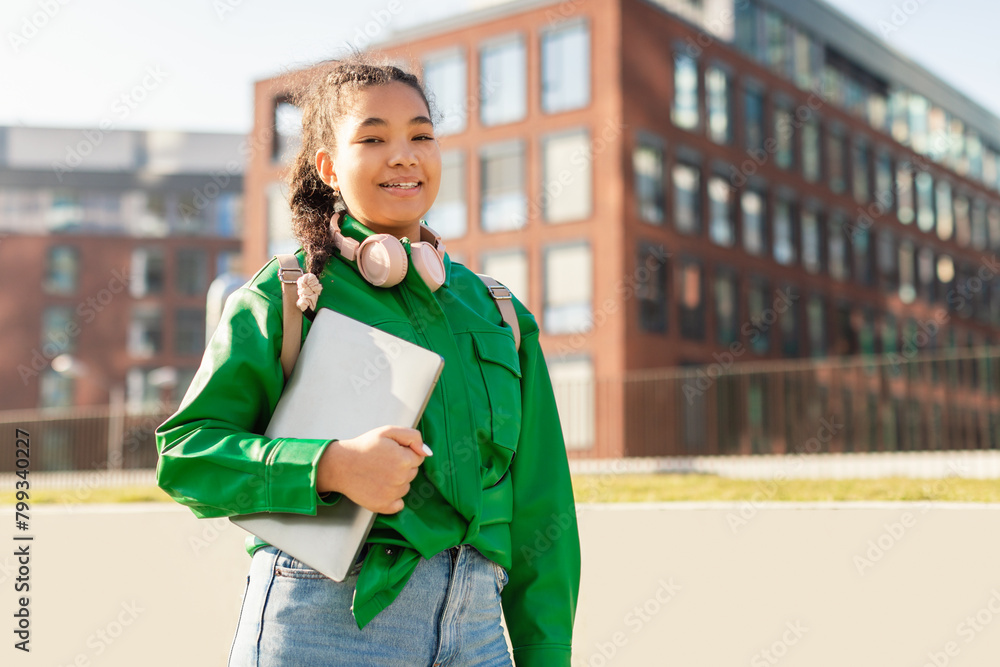 Fototapeta premium Girl in a Green Jacket Holding a Laptop