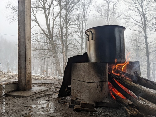 Maple sap boiling in a large pot over a fire to evaporate down into maple syrup