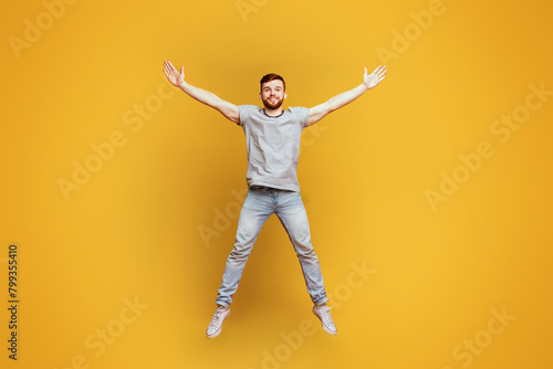 Energetic Man Jumping With Arms Outstretched © Prostock-studio