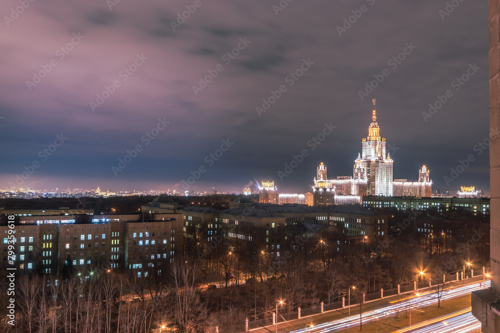 Twilight View of a Majestic University Building Illuminated in Moscow. The city lights begin to glow. The vantage point from a high-rise showcases an urban landscape