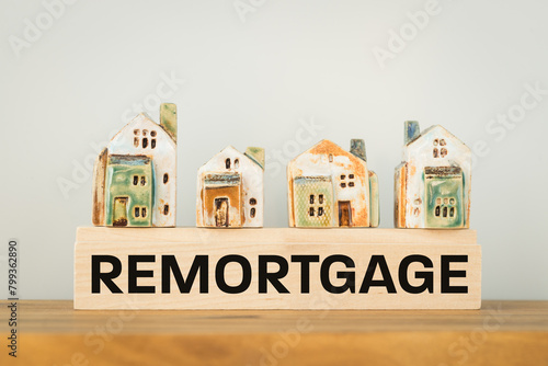 REMORTGAGE, a word written on a wooden block with miniature houses. Real estate business and financial concept, copy space photo