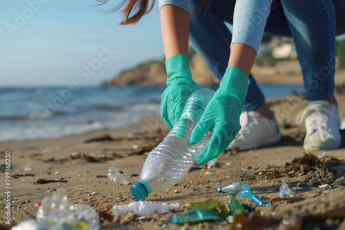 Woman in rubber gloves picking plastic bottles on the beach. photo