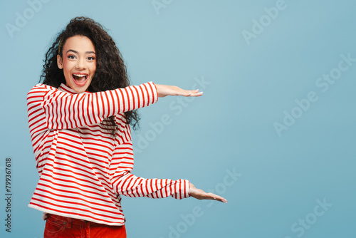 Foto Amazed excited girl, teenager with Afro hairstyle showing huge size of imaginary