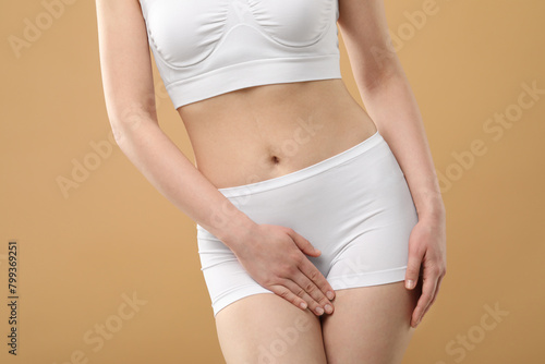 Woman suffering from cystitis on beige background, closeup