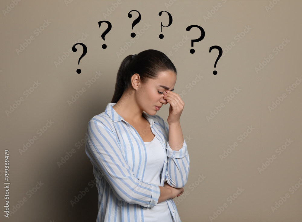 Amnesia. Confused young woman and question marks on beige background Amnesia. Confused young woman and question marks on beige background