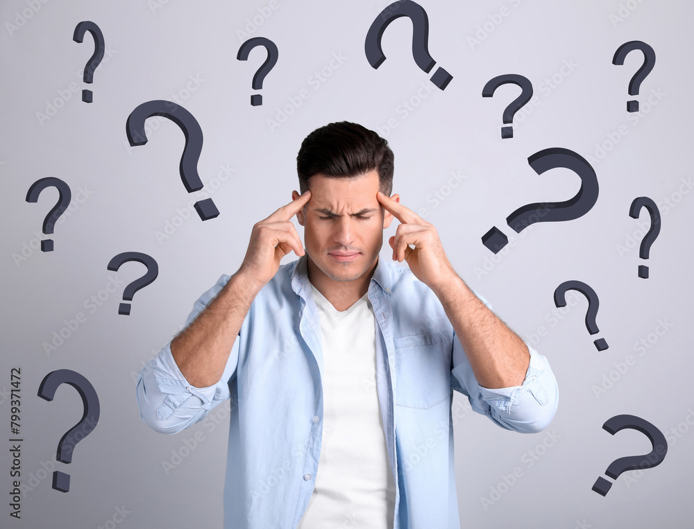 Amnesia. Confused man and question marks on light background Amnesia. Confused man and question marks on light background