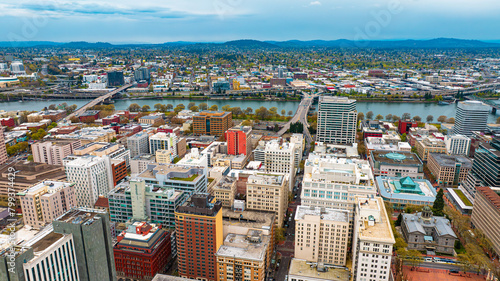 Downtown of Portland, Oregon, the USA with high-rise architecture. Twilight view of the city with mountain silhouettes at backdrop.