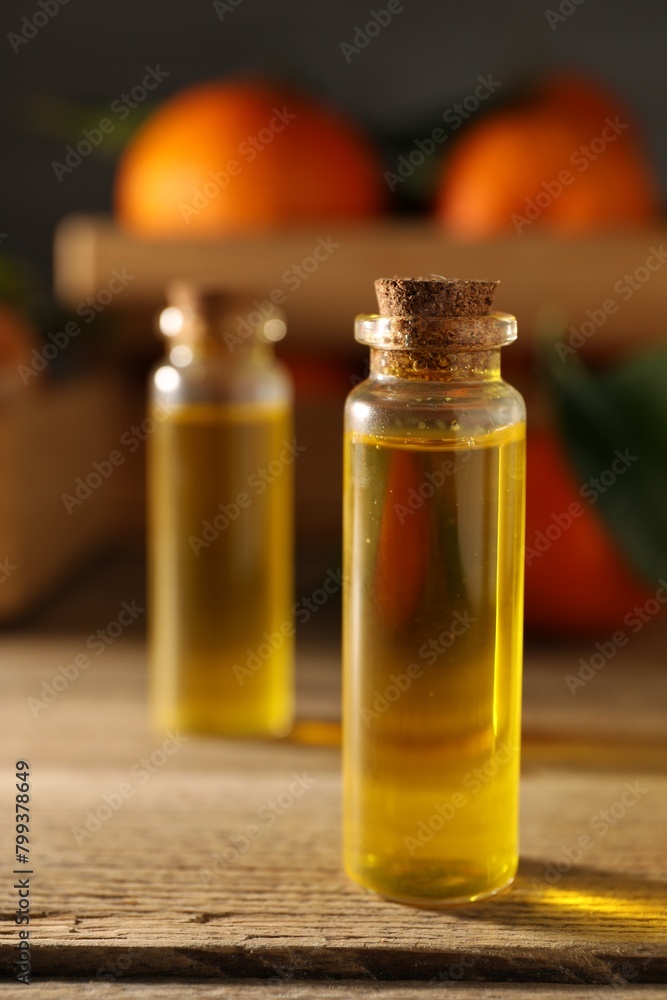 Bottles of tangerine essential oil on wooden table, closeup Bottles of tangerine essential oil on wooden table, closeup