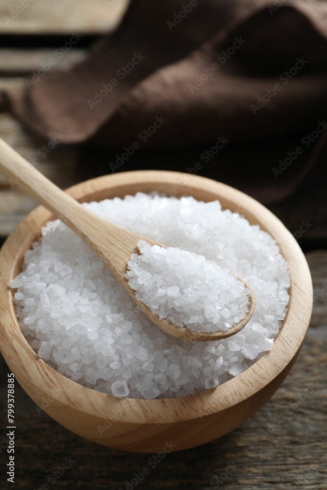 Organic salt in bowl and spoon on wooden table, closeup Organic salt in bowl and spoon on wooden table, closeup
