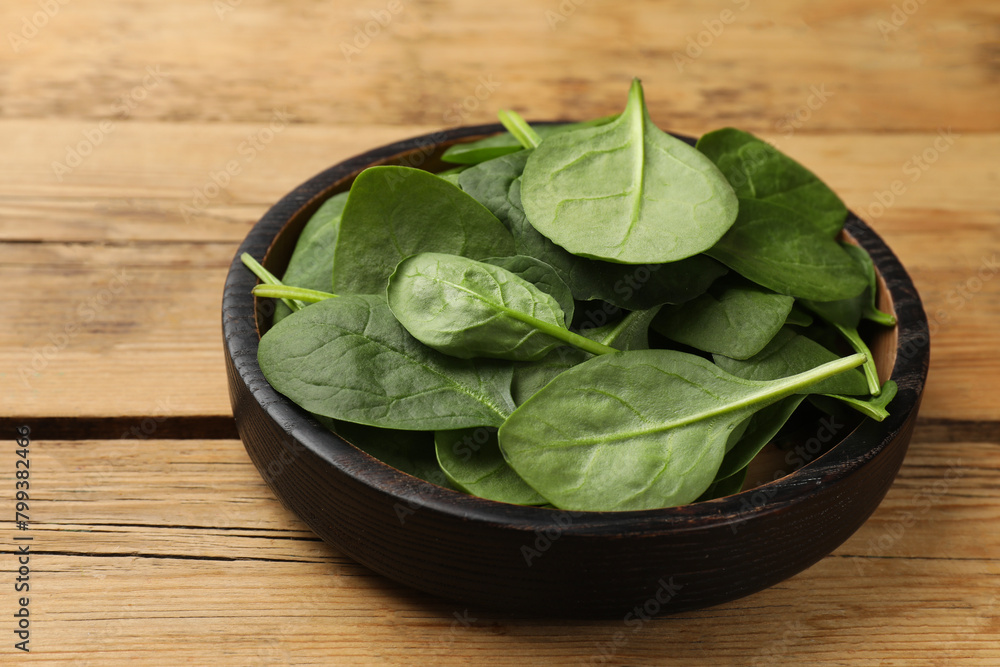 Fresh spinach leaves in bowl on wooden table, closeup Fresh spinach leaves in bowl on wooden table, closeup