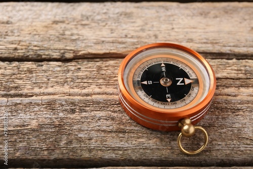 One compass on wooden table, space for text