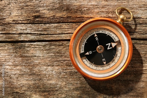 One compass on wooden table, top view. Space for text