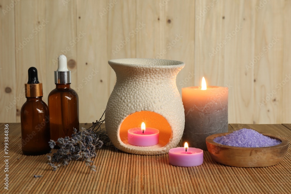 Aromatherapy. Scented candles, bottles, lavender and sea salt on bamboo mat