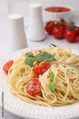 Tasty pasta with tomato, cheese and basil on table, closeup