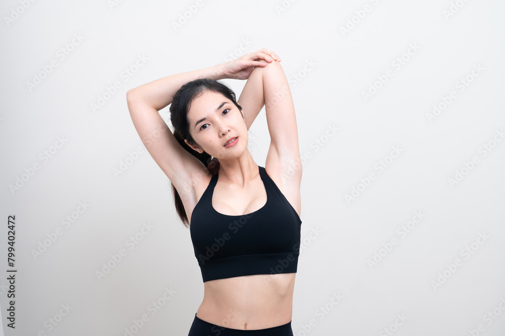 Attractive Asian woman in black workout clothes doing arm stretching on white background. Confident young female athlete body warm up before workout on isolated. Attractive Asian woman in black workout clothes doing arm stretching on white background. Confident young female athlete body warm up before workout on isolated.