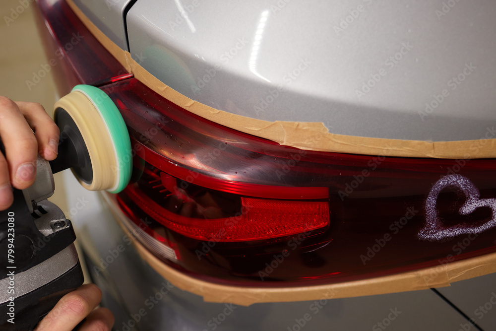 Fototapeta premium Person using a machine to polish automotive lighting on a car headlight