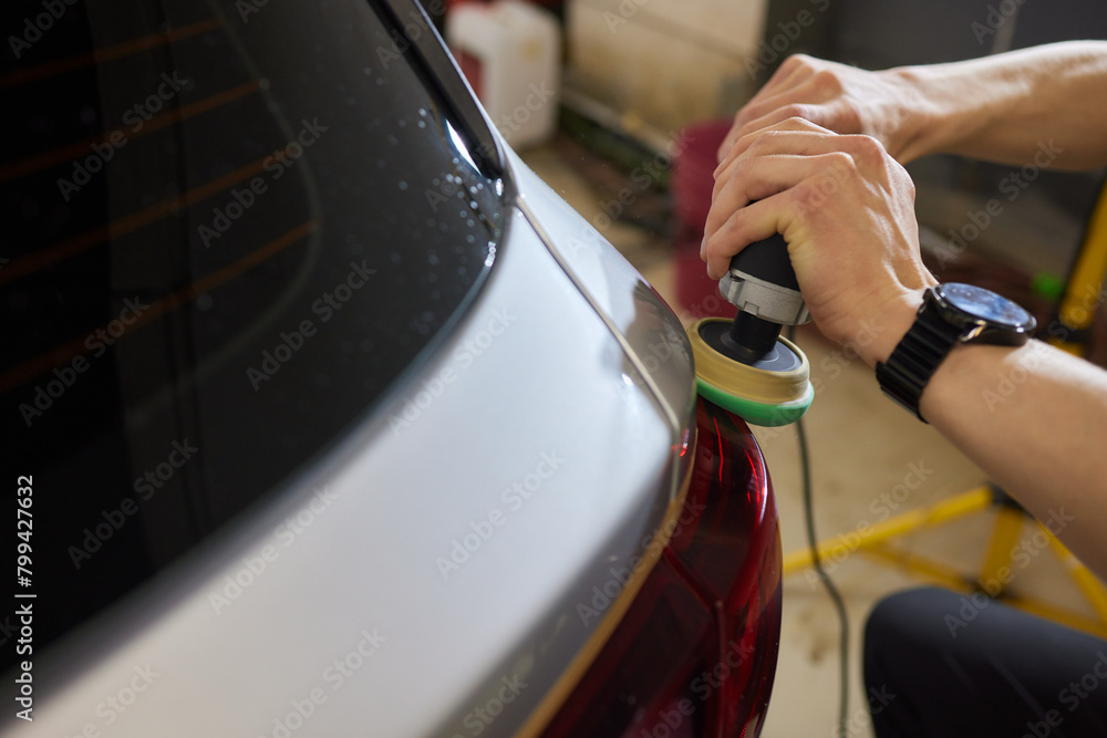 Obraz premium Person using a machine to polish automotive lighting on a car headlight