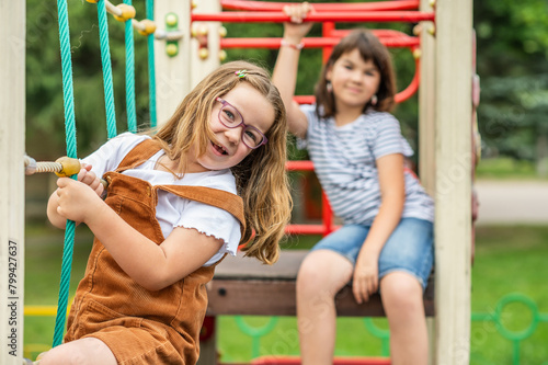 portrait of children, a happy smiling girl of 11 years old and a girl of 6 years old playing on a children's playground. looking at the camera close-up.