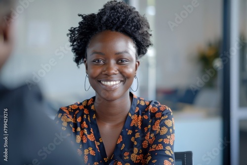 A joyful African woman smiling during a pleasant conversation in the office environment © ChaoticMind