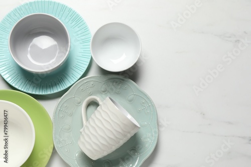 Beautiful ceramic dishware and cup on white marble table, flat lay. Space for text