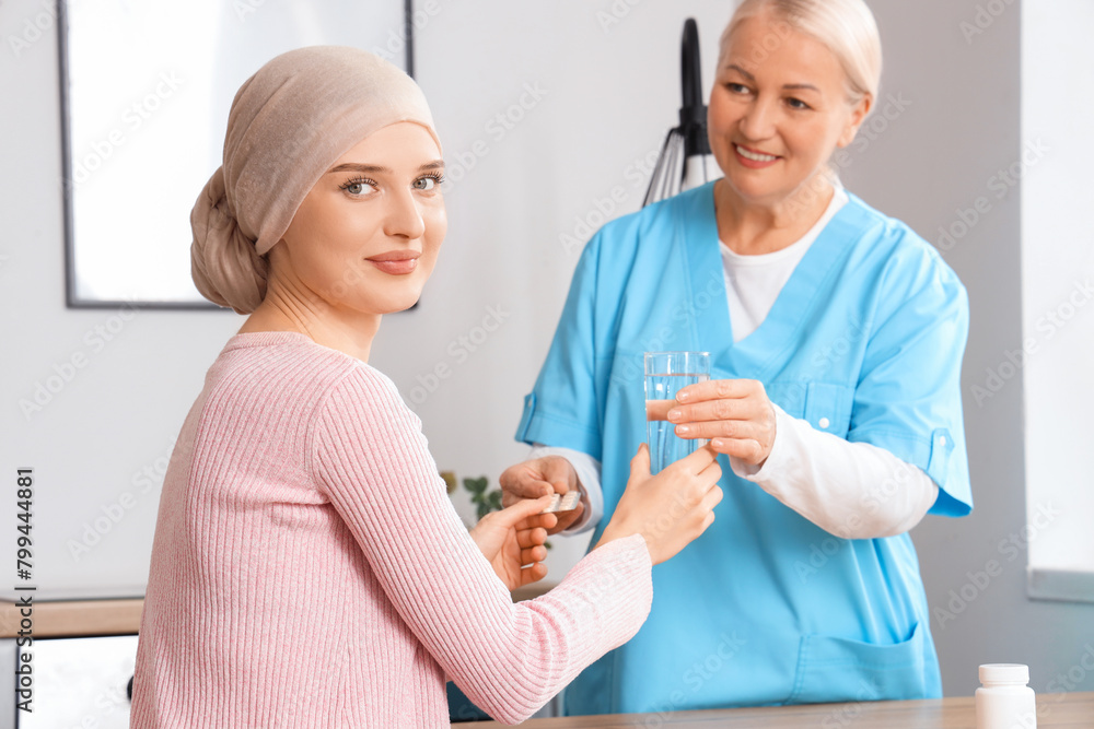 Young woman after chemotherapy taking pills from nurse in kitchen. Stomach cancer concept Young woman after chemotherapy taking pills from nurse in kitchen. Stomach cancer concept