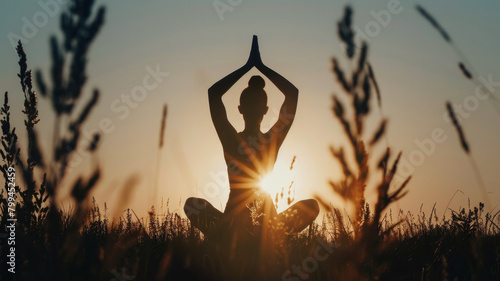 The silhouette of a woman in a yoga pose in a field at sunrise. The unity of man with nature, meditation. International Yoga Day