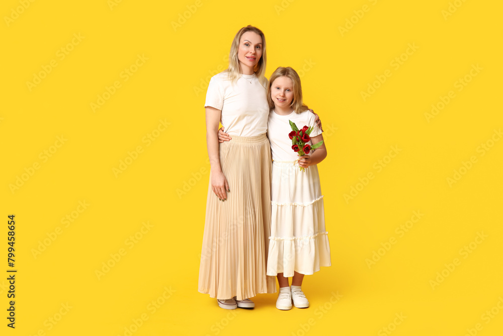 Cute little girl with her mom and bouquet for Mother's Day on yellow background