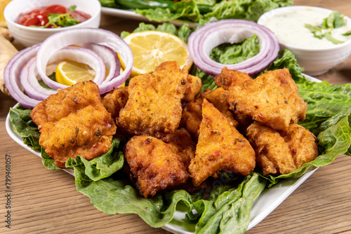 A plate of traditional Indian or Pakistani Fish Pakora, basa fish dipped in chick pea batter and deep fried photo